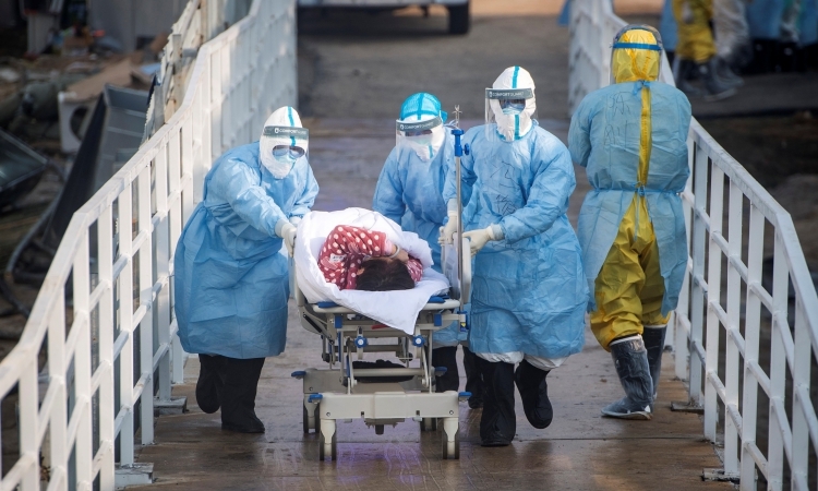 Nhân viên y tế đưa bệnh nhân nhiễm virus corona vào bệnh viện dã chiến ở Vũ Hán, tỉnh Hồ Bắc, Trung Quốc, hôm 4/2. Ảnh: Reuters. 